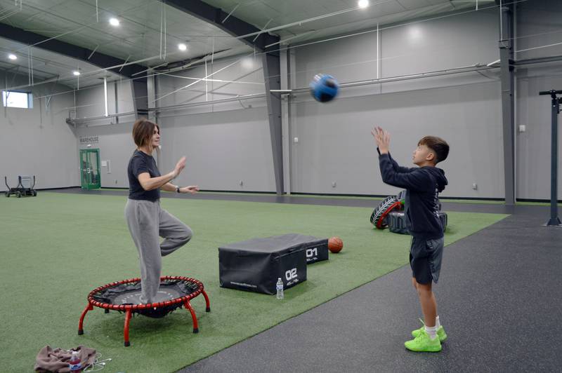 Kelly Escamilla, of Sterling, tosses a ball back and forth with her son, Easton Escamilla, as she bounces on a trampoline at Westwood Fitness & Sports Center Building 1 on Tuesday, Nov. 21, 2023. Westwood is one of the Sterling Park District's many parks and facilities.