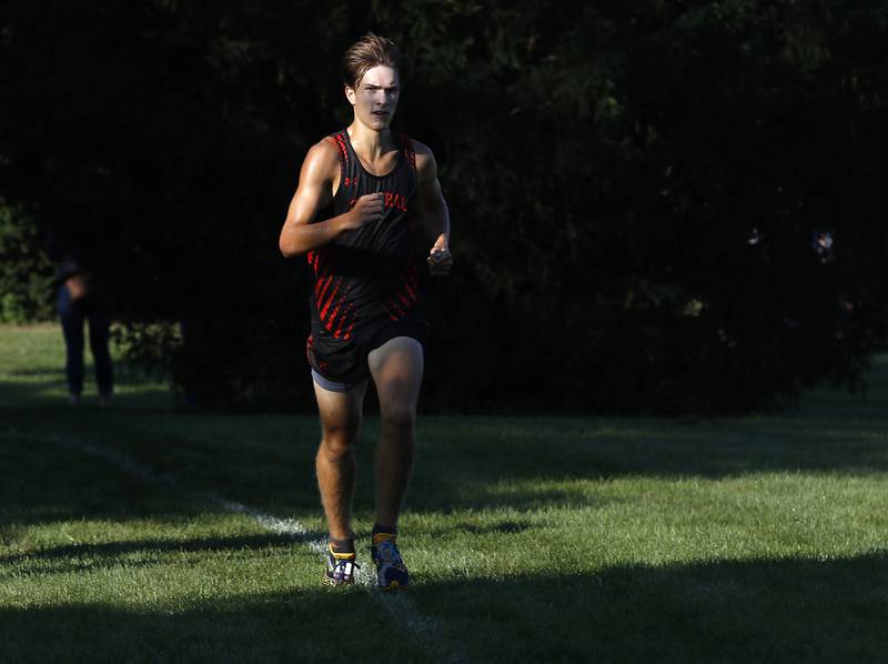 Crystal Lake Central’s Karson Hollander runs through the shadows on his way to winning the boys race of the McHenry County Cross Country Meet Saturday, August 27, 2022, at Emricson Park in Woodstock.