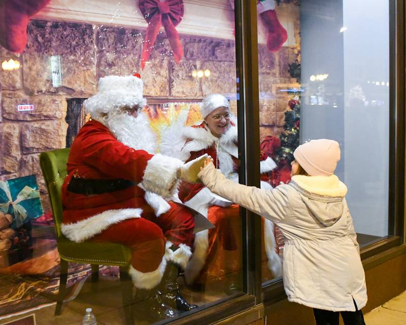 Anna Neal, 6, of Sycamore gives Santa Claus a high five during the Sycamore Chamber of Commerce's annual Moonlight Magic event held in downtown Sycamore on Friday, Nov. 17, 2023.