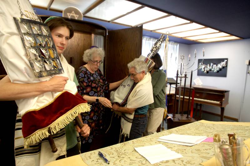 Rabbi Maralee Gordon assists members in removing Torah Scrolls as the McHenry County Jewish Congregation held a deconsecration ceremony at their Ridgefield Road location in preparation for a move to the Tree of Life Unitarian Church in McHenry on Sunday, August 18. Mezuzot were removed from doorways and the Torah Scrolls were removed from their ark and transported  to the new building as worshipers consecrated the new building as their synagogue.