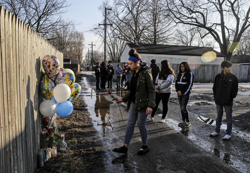 Friends of 13-year-old Javier Cayetano place balloons, candles and flowers on a memorial Feb. 22 in the alleyway on Moran Street where Cayetano was shot the day before in Joliet.