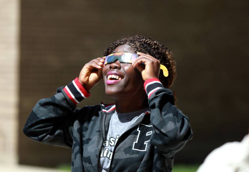 Abigail Duor of Sugar Grove looks at the sun using special protective glasses during the solar eclipse on Monday, April 8, 2024 at Waubonsee Community College in Sugar Grove.