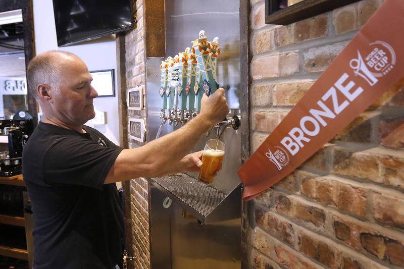 Brewmaster Ryan Clooney ours a beer beer on Friday, May 3, 2024 at the Crystal Lake Brewing. The brewery is celebrating its 10th anniversary and recently won a bronze award in Brown Porter category at the World Beer Cup in Las Vegas.