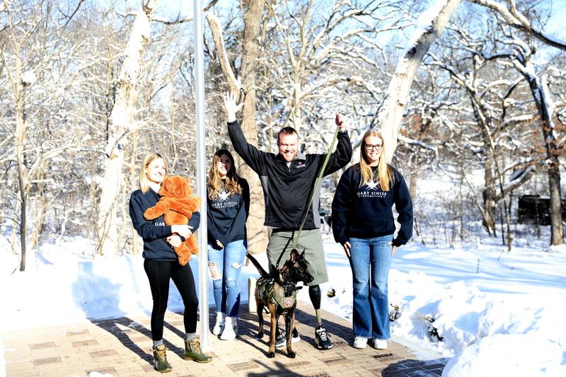 Retired U.S. Army Chief Warrant Officer 2 Patrick Scrogin, along with wife Alexa, service dog, Kiowa, and children Wyatt, Paige and Kaylee, celebrate raising American and Army flags for his family’s newly constructed, specially adapted smart home in St. Charles on Thursday, Jan. 18, 2024. The mortgage-free home was made possible by the Gary Sinise Foundation.