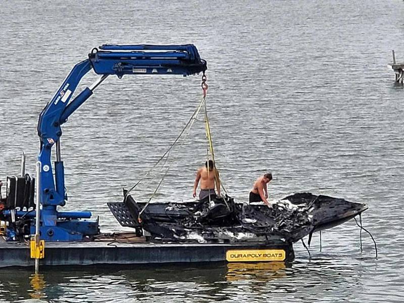 Two people examine the wreckage of a small boat that was on fire earlier Sunday, Aug. 6, 2023, in Pistakee Lake.