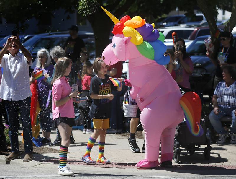 Dr. Raymond Pryor, dressed in a unicorn costume from Secure Alliance Counseling hands out a pride flag during the Woodstock PrideFest Parade on Sunday, June 9, 2024, around the historic Woodstock Square.