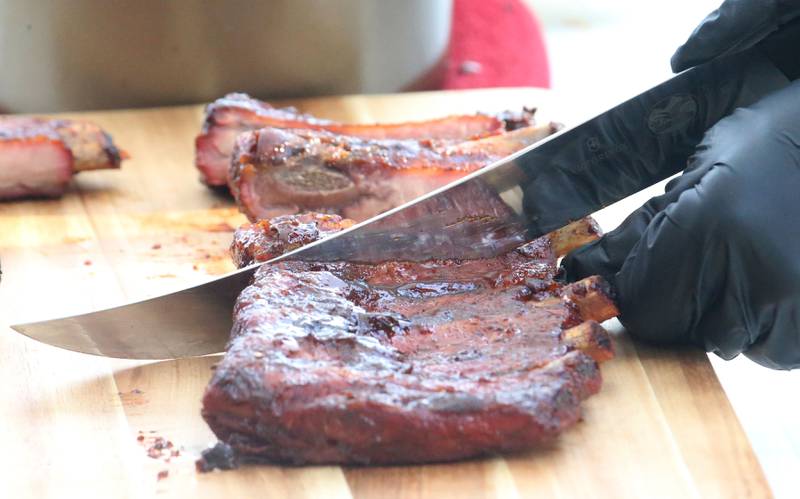 Grillmasters slice bbq ribs during the BBQ and Blues festival on Friday, Sept. 13, 2024 downtown La Salle.