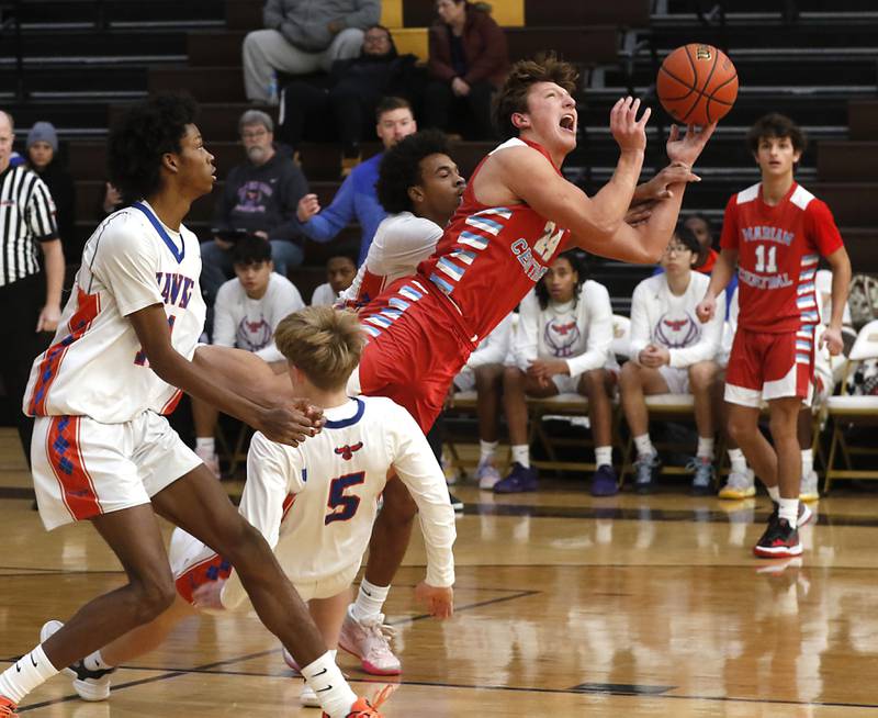 Marian Central's Christian Bentancur drives to the basket against Hoffman Estates’ DJ Wallace, (left)  Connor Kurzynski (center) and (center) Trendell Whiting (right) during a Hinkle Holiday Classic basketball game Tuesday, Dec. 27, 2022, at Jacobs High School in Algonquin.