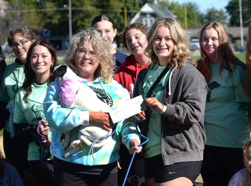 Alayna Young presents a $500 donation to Michelle Longtin of Happy Tails Humane Society following Polo High School's 2024 Doggy Dash on Saturday, Sept. 7, 2024. Longtin is holding Ashley, one of the dogs currently available for adoption. Also pictured are Polo Student Council members Gracie Woodin, Abbie Barron, Macie Mandrell,  Jilli Gorzny, and Emily Kitson. The event was organized and run by the student council and also included a costume contest.