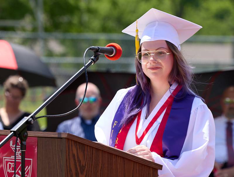 Hall class president Grace Wozek presents the class gift of landscaping in front of the cafeteria windows during graduation on Sunday, May 19, 2024 at Hall High School.