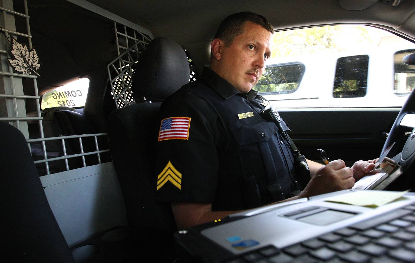 Shaw Local June 2011 file photo – Genoa Police Sgt. Robert Smith glances at his computer while on a traffic stop where he issued a warning to the driver for not wearing a seat belt in Genoa on Tuesday, June 28, 2011. Behind Smith is the kennel for a K-9 officer.