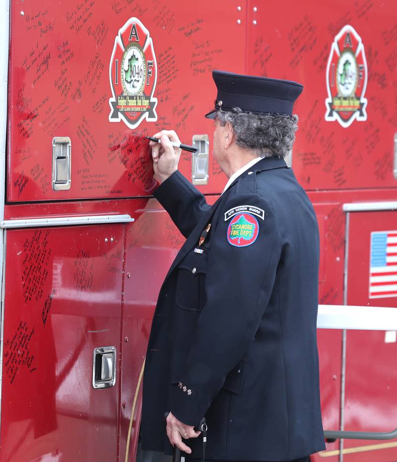A retired Sycamore firefighter writes a message on a vintage fire truck for firefighter/paramedic Bradley Belanger Saturday, Jan. 6, 2024, during the visitation for Belanger at the Sycamore Park District Community Center. Belanger, 45, who worked with the Sycamore Fire Department for more than two decades, died Friday, Dec. 22, after a yearlong battle with cancer.