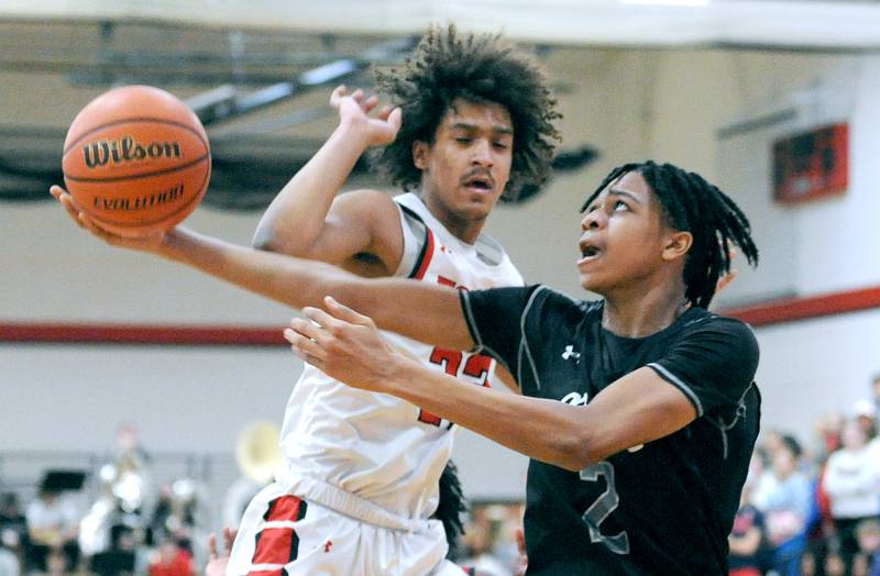 Oswego East's Mason Lockett IV (2) attempts a reverse layup against Yorkville defender Jory Boley during a varsity basketball game at Yorkville High School on Friday, Feb. 9, 2024.