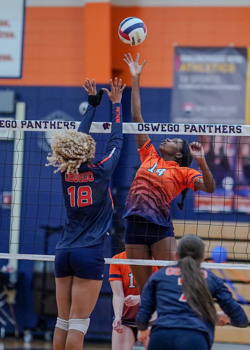 Romeoville's Demi Cole (14) plays the ball at the net against Oswego’s Maya Norlin (18) during a volleyball game at Oswego High School on Tuesday, Oct. 17, 2023.