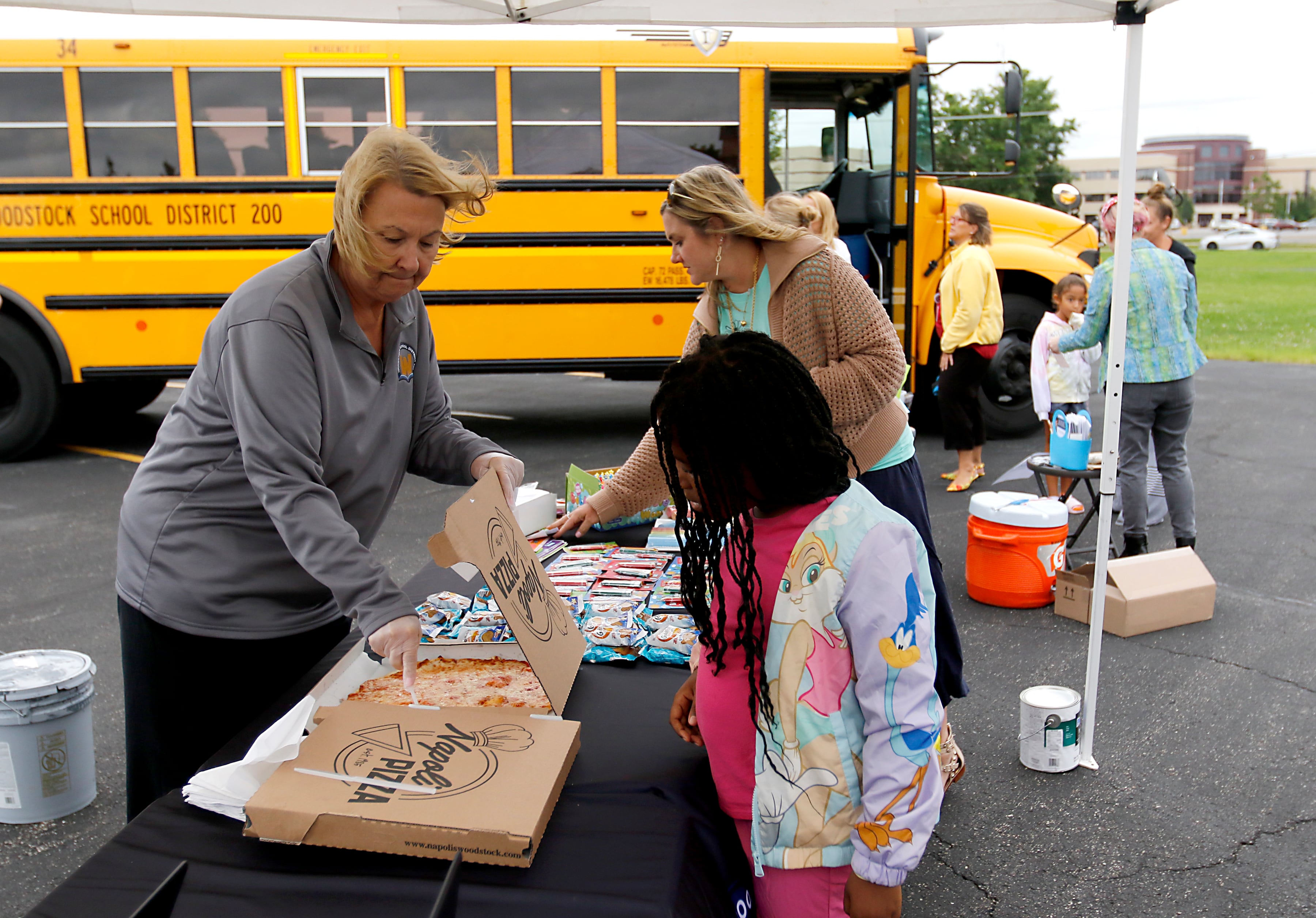 Pizza is handed out to children during a Woodstock School District 200 Back to School Coming to You event at Northwood Middle School on Tuesday, Aug. 6, 2024. The location was one of twelve stops on the tour that gave out backpacks and school supplies, provided registration help and computer repair.