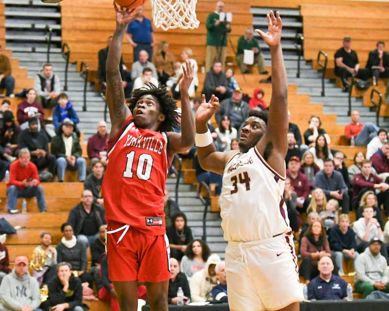 Yorkville's Kaevian Johnson (10) makes a basket while being defended by St. Ignatius's Justin Scott (34) in the second half of the game on Tuesday Dec. 26, 2023, during the Jack Tosh tournament held at York High School in Elmhurst.