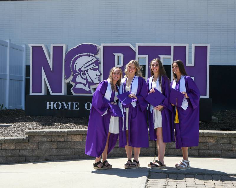 Downers Grove North seniors Abbey Kloss, Ashley Johnson, Maddie Kloss and Rlie Conway all pose in front of the Downers Grove North sign near the football field before the start of the graduation ceremony held at Downers Grove North High School football field on Sunday May 19, 2024.