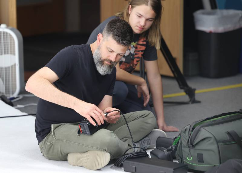 Dave Fowler, (seated) and Lucas Deming, son of project director Seth Deming, set up equipment for shooting a scene for a project that is part of the group Write, Film, Edit Thursday, May 16, 2024, in the studio at OC Creative in DeKalb.