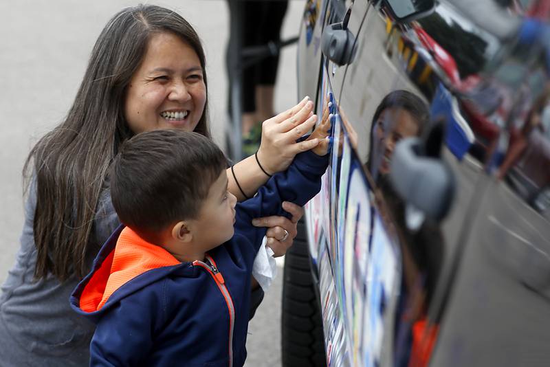 Greyson Van Huss, 2, of McHenry, gets some help from his mom, Heather as he adds his hand print to a McHenry Police Department squad car the during a National Night Out event Tuesday, Aug. 6, 2024, at Petersen Park in McHenry.