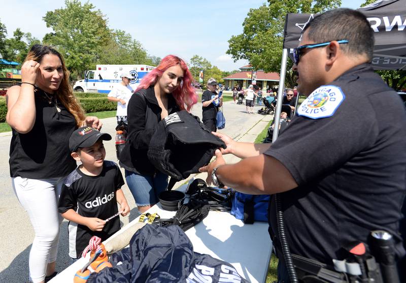 Chicago Police Officer, Sergio Valdez discusses some of the necessary equipment needed while on duty with (left-right) Marilu Hernandez and her children Henry and Amy Villegas of Lombard during the First Responders event held at Brookfield Zoo Sunday Aug 28, 2022.