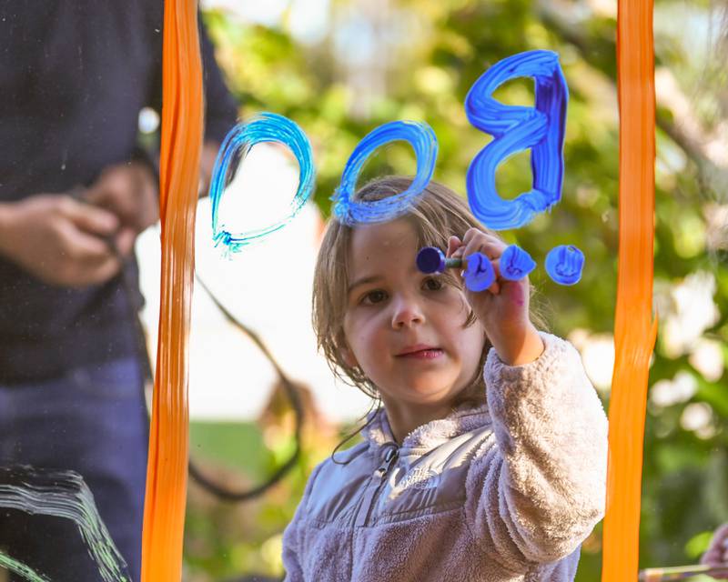 Abigail Ketterhagen, 3 years old, of Downers Grove helps paint a window during the Halloween Window painting event held downtown Downers Grove on Saturday Oct. 21, 2023.