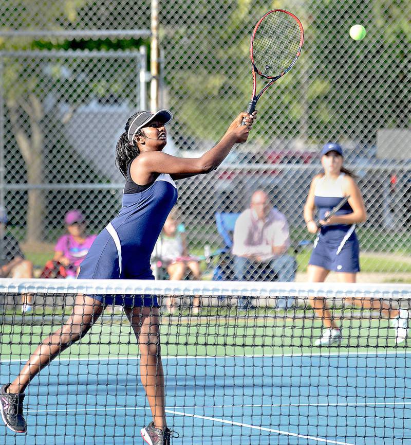 Oswego East's Keertana Kota smashes a shot at the net, while her teammate Annie Carmody watches in the background during a double match against Yorkville at a girls tennis meet at Yorkville High School on Monday, Sept. 12.