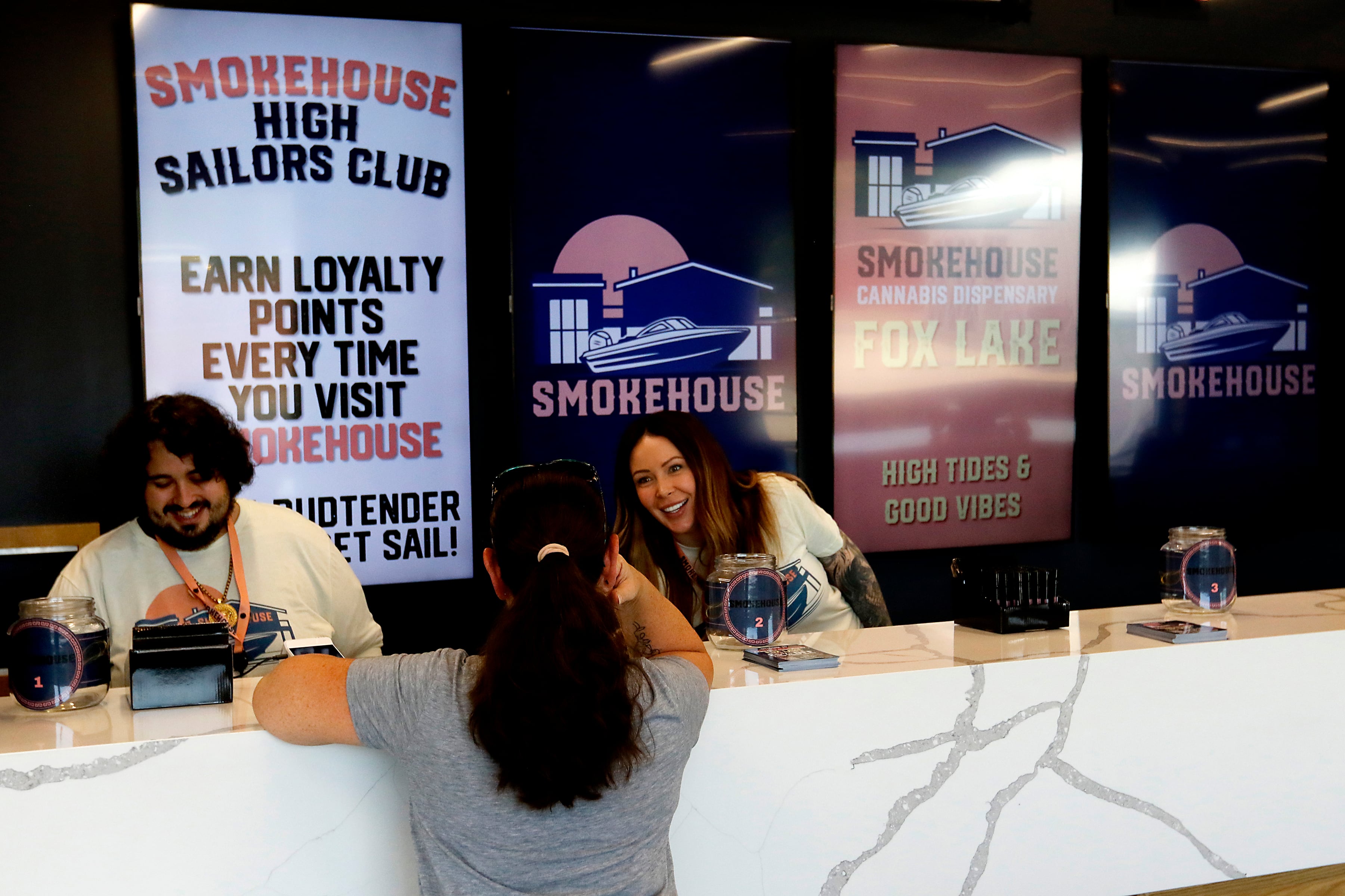 Smokehouse manager Anthony Bernardini  and Agent in Charge Madeline Morgan help a customer at Illinois’ first dispensary located right on the water in Fox Lake on Friday, July 25,2024. The dispensary located at 44 U.S. Route 12, features boat slips so customers on the Fox River and Chain O' Lakes can boat right up to the dispensary.