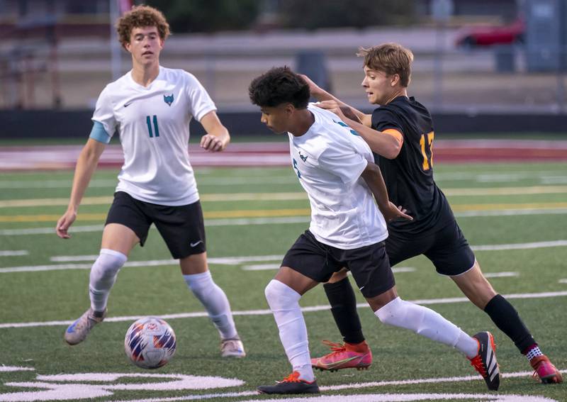 Woodstock North's Saul Santana, center, holds off Richmond-Burton's Joe Kyes during their varsity soccer game on Wednesday, September 18, 2024 at Richmond-Burton High School in Richmond.