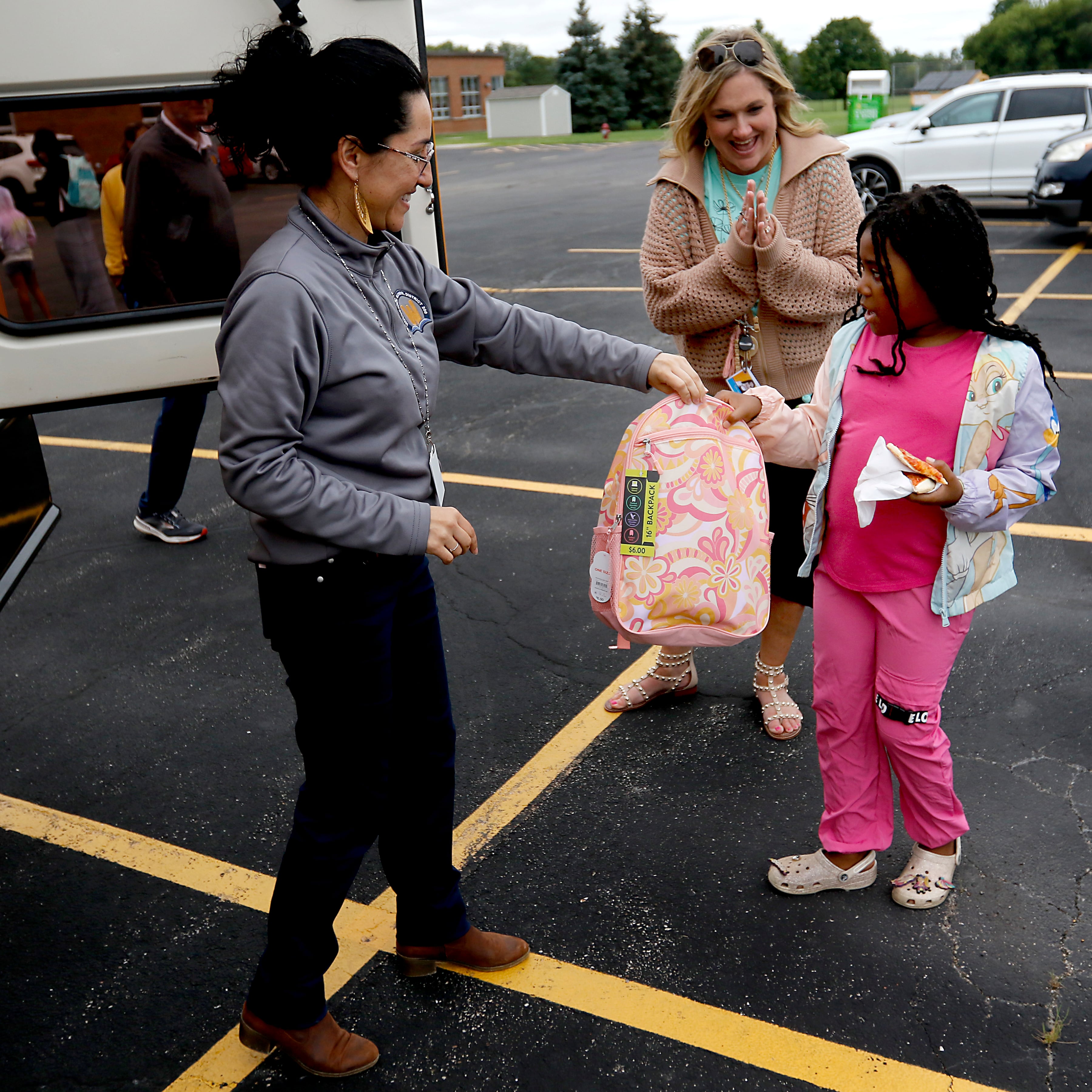 Gabi Ordonez hands JaKayla Ruffin an backpack during a Woodstock School District 200 Back to School Coming to You event at Northwood Middle School on Tuesday, Aug. 6, 2024. The location was one of twelve stops on the tour that gave out backpacks and school supplies, provided registration help and computer repair.