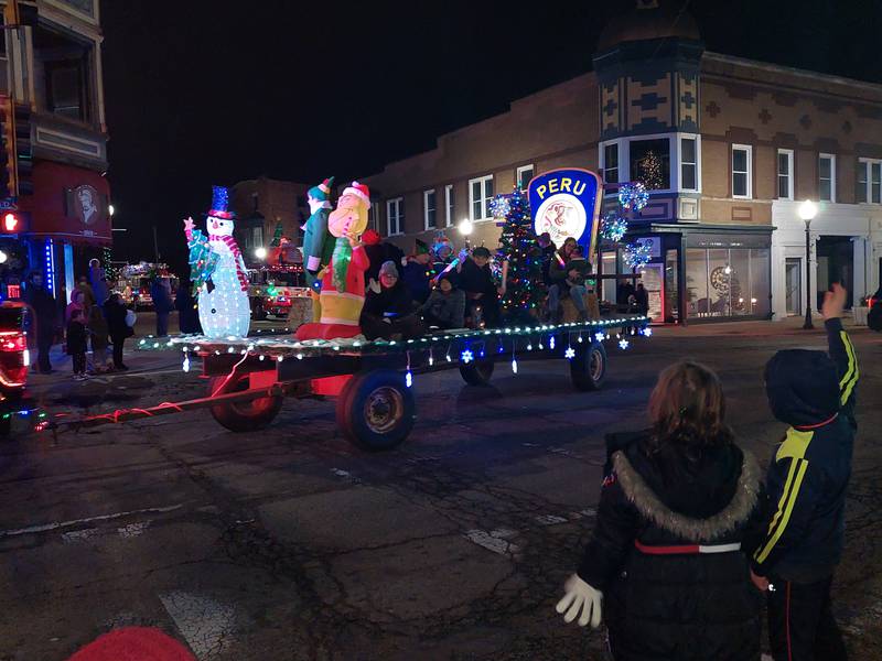 Children watch a Peru Police Department float ride by Saturday, Dec. 2, 2023, during the Lighted Christmas Parade in Peru.