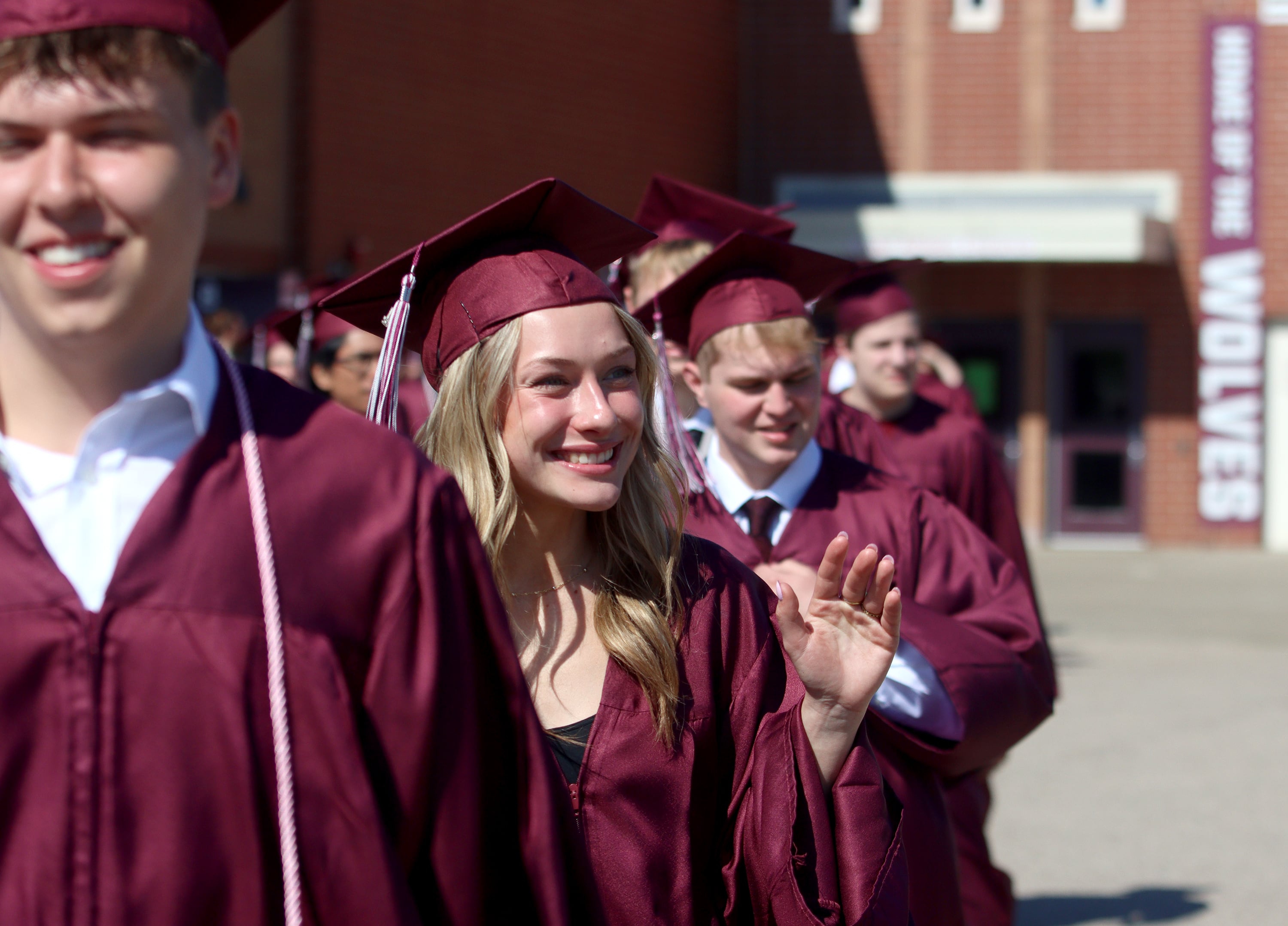 Isabelle Karasek waves as she marches toward Prairie Ridge High School’s commencement at the school in Crystal Lake on Saturday.