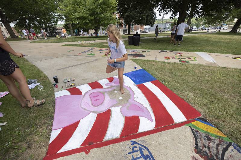 Lyndie Kaster, 11, and mom Emily Seier participate in a patriotic pig painting for Petunia fest Monday, July 3, 2023 during this festival’s Brush and Bloom event. Buddiing artists decorated the sidewalks around the Old Lee County Courthouse for the colorful event.