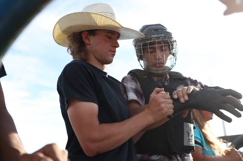 As a more advanced bull rider Dominic Dubberstine-Ellerbrock, left, helps a newer rider ready up before a ride. Dominic will be competing in the 2022 National High School Finals Rodeo Bull Riding event on July 17th through the 23rd in Wyoming. Thursday, June 30, 2022 in Grand Ridge.