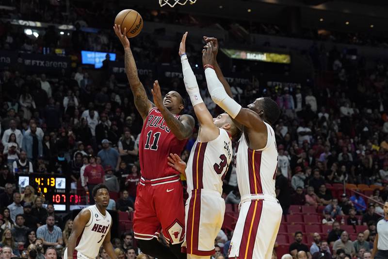 Chicago Bulls forward DeMar DeRozan (11) drives to the basket as Miami Heat guard Max Strus (31) and center Bam Adebayo (13) defend, during the first half of an NBA game Wednesday, Oct. 19, 2022, in Miami. (AP Photo/Marta Lavandier)