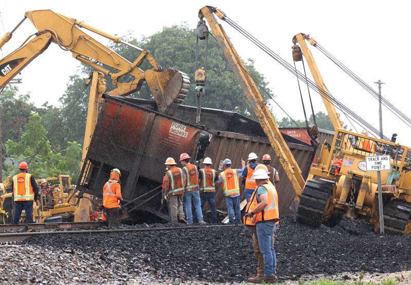 Workers watch as cranes and a loader upright a tipped over coal car after a BNSF Railway train traveling east derailed Wednesday, July 10, 2024, near Route 34 on the west side of Somonauk.