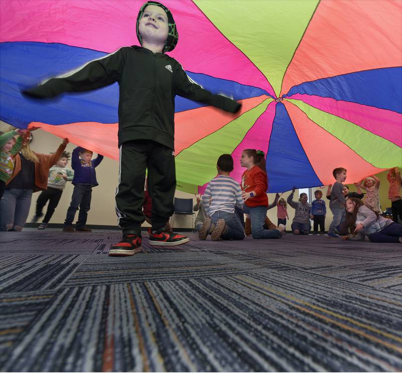 While parents help children lift up the parachute, other children were able to climb under during the Parachute Play program Friday at the Reddick Library in Ottawa.
