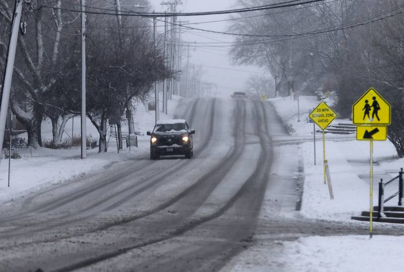 A vehicle navigates snow covered pavements on West South Street in Woodstock as a winter storm moves through McHenry County on Tuesday, Jan. 9, 2024, delivering snow to most of the county.