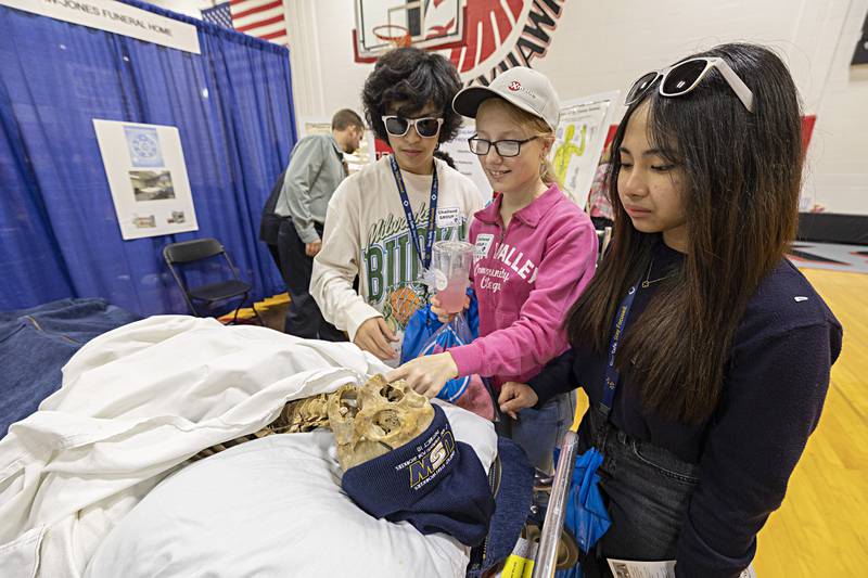 Challand eighth-graders Jabez Garcia (left) Leah Leesman and Yuzziah Quinivista check out “Jones’ Bones” at the booth of the Law-Jones Funeral Home Friday, Oct. 20, 2023.