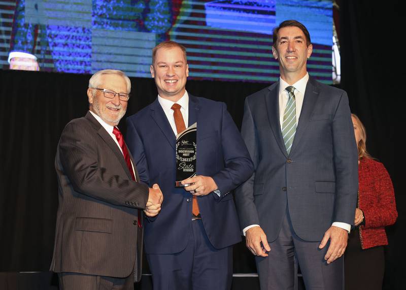 llinois Farm Bureau Young Leader Discussion Meet Winner Austin Granby (center) of Grundy County, also a La Salle County business owner, accepts the state award from former IFB President Richard Guebert Jr. (left) and COUNTRY Financial CEO Jim Jacobs on stage during the organization’s annual meeting Dec. 3, 2023, in Chicago.