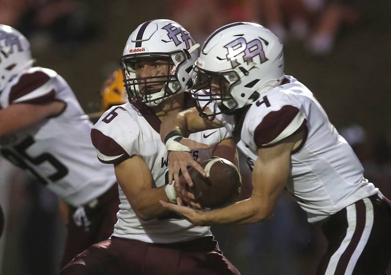 Prairie Ridge's Luke Vanderwiel hands the ball off to Jack Finn during a Fox Valley Conference football game against Jacobs on Friday, Aug 30, 2024, at Jacobs High School in Algonquin.