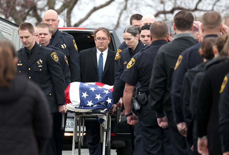 DeKalb County Sheriff’s Deputies remove the flag-draped gurney carrying the body of DeKalb County Sheriff’s Deputy Christina Musil from the Hearse Monday, April 1, 2024, at Butala Funeral Home following the processional honoring the fallen officer. Musil, 35, was killed Thursday while on duty after a truck rear-ended her police vehicle in Waterman.