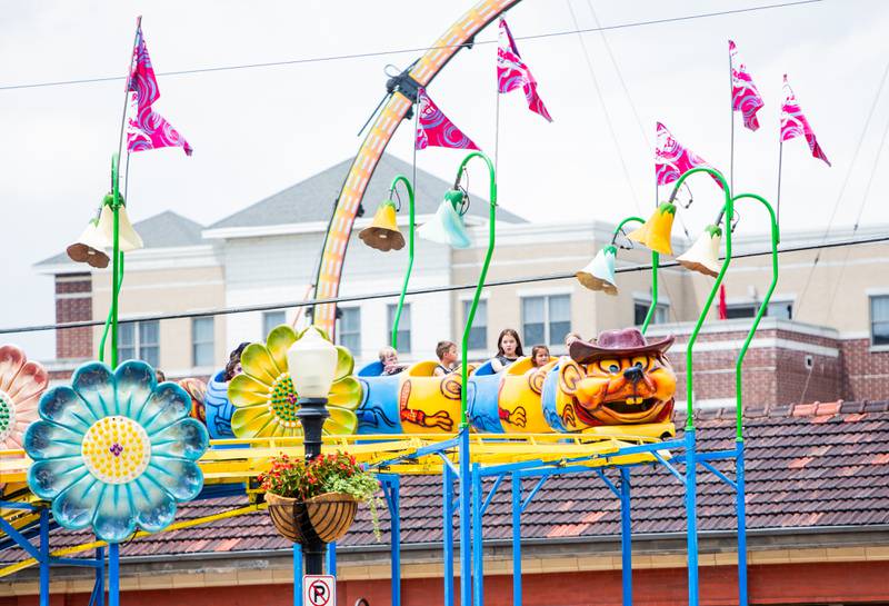 A roller coaster carrying festival goers zooms over the train station during the Downer’s Grove Rotary Fest, Saturday, June 22, 2024.