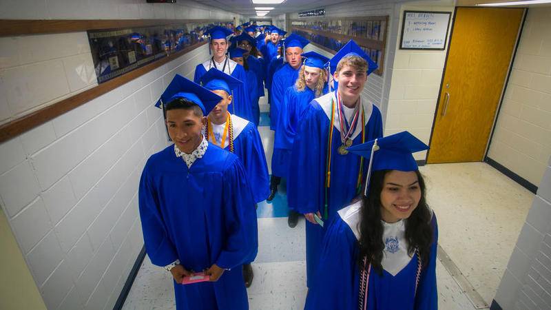 Angel Ayala (front-left) and Amber Acevedo (front-right) lead fellow graduates down the hallway May 19 for the final time as students and into the Woodstock High School graduation ceremony at Woodstock High School in Woodstock.