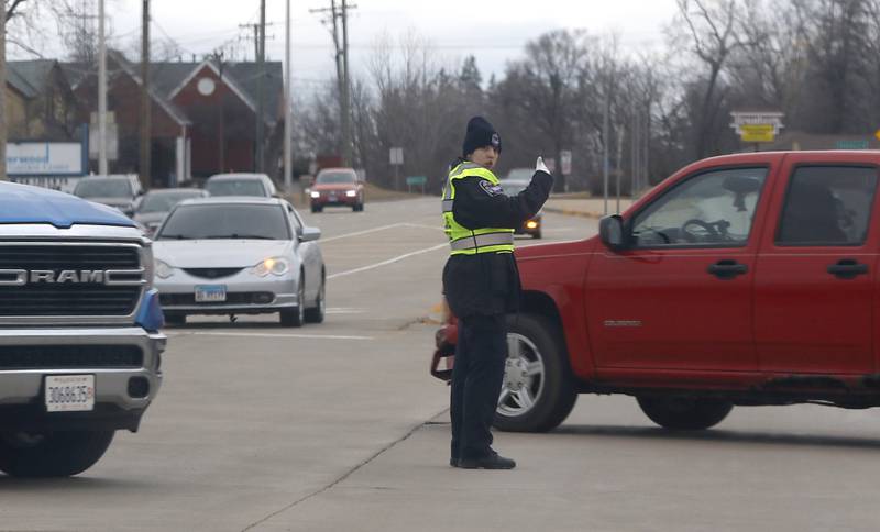 A Crystal Lake police officer directs traffic at the intersection of Route 176 and Route 14 where the traffic lights were not operating on Thursday, Feb. 23, 2023, as county residents recover from a winter storm that knocked down trees and created power outages throughout McHenry County.