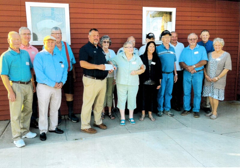 (From left) Larry Baxter, Lynn Misselt, Robert Sebby, Don Revelle, Superintendent Rich Faivre, Karen Risk, Elaine Ostrem, Richard Selvig, Jane Walters, Darrell Cochran, John Hougas, Dale Morsch, Jim Temple, Robert Combs and Emma Larson take part in a donation from the Serena High School Class of 1964 to the school.