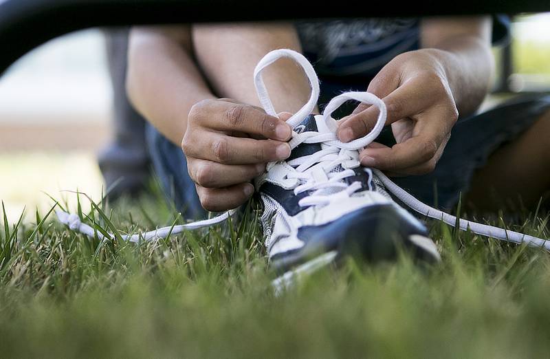 Samuel Resendez, 6, ties the shoelaces of his new shoes during the back to school event Thursday at the DeKalb County Government Center in DeKalb.