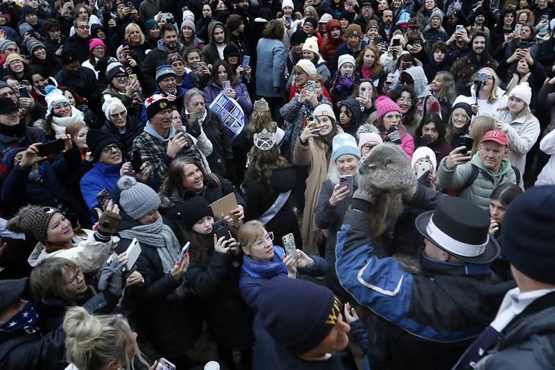 Woodstock Willie is held by handler Mark Szafran aloft as they make their way through a crowd after Willie predicted an early spring on Friday, Feb. 2, 2024, during the annual Groundhog Day Prognostication on the Woodstock Square.