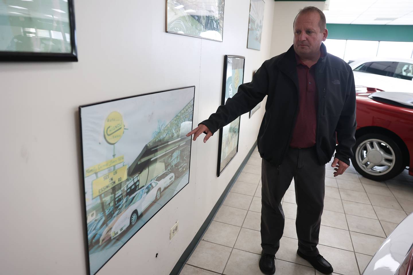 Gregg Chignoli point to a photo of their old 660 Theodore Street auto dealership in the show room of Chignoli Auto in Joliet on Saturday, Oct. 28, 2023.