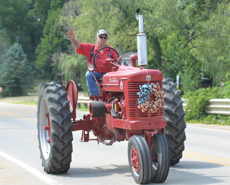 Cliff Jones of Ashton waves to onlookers as he drives his Farmall on Daysville Road during the Living History Antique Equipment Association's tractor drive on Saturday. About 40 tractors took part in the ride that started at the association's show grounds in Franklin Grove and traveled to Oregon and back.