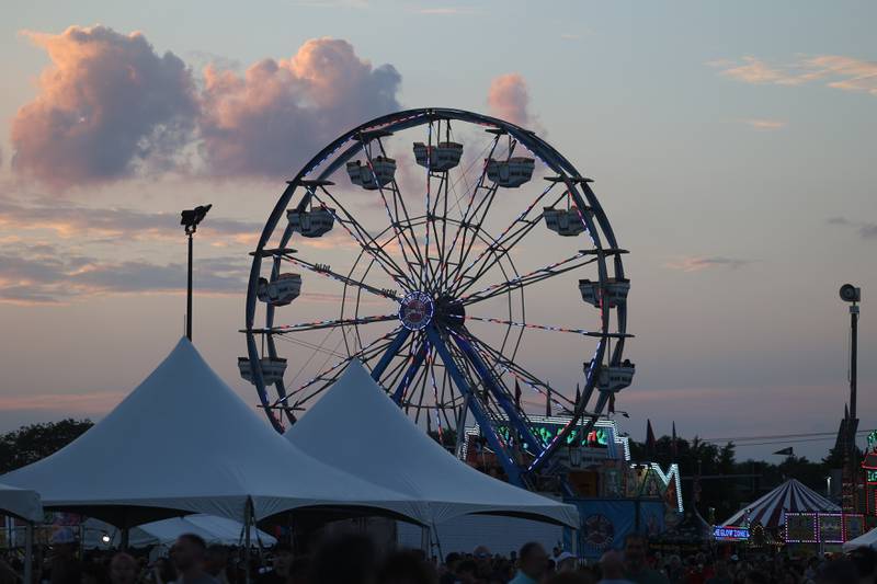 The sun sets while people ride the Ferris Wheel at the Taste of Joliet on Friday, June 21, 2024 at Joliet Memorial Stadium.